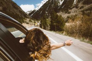 girls hangs out of car window with wind in her hair